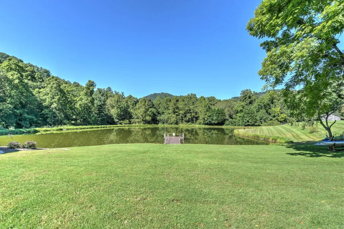 This tranquil image displays a calm pond surrounded by lush greenery and distant mountains, inviting fishing, picnicking, and quiet exploration. The natural beauty and open space create an inviting setting for families to spend time together outdoors, whether fishing or simply enjoying the view.