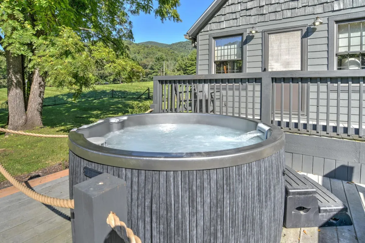 A private hot tub sits just outside the house, surrounded by nature and offering unobstructed views of the landscape. The atmosphere is tranquil and inviting; you can easily imagine soaking together while gazing at the stars or enjoying sunset moments.